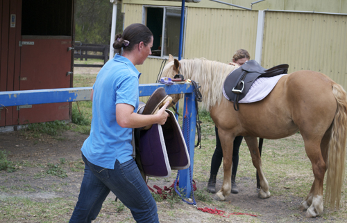 people unsaddling horses